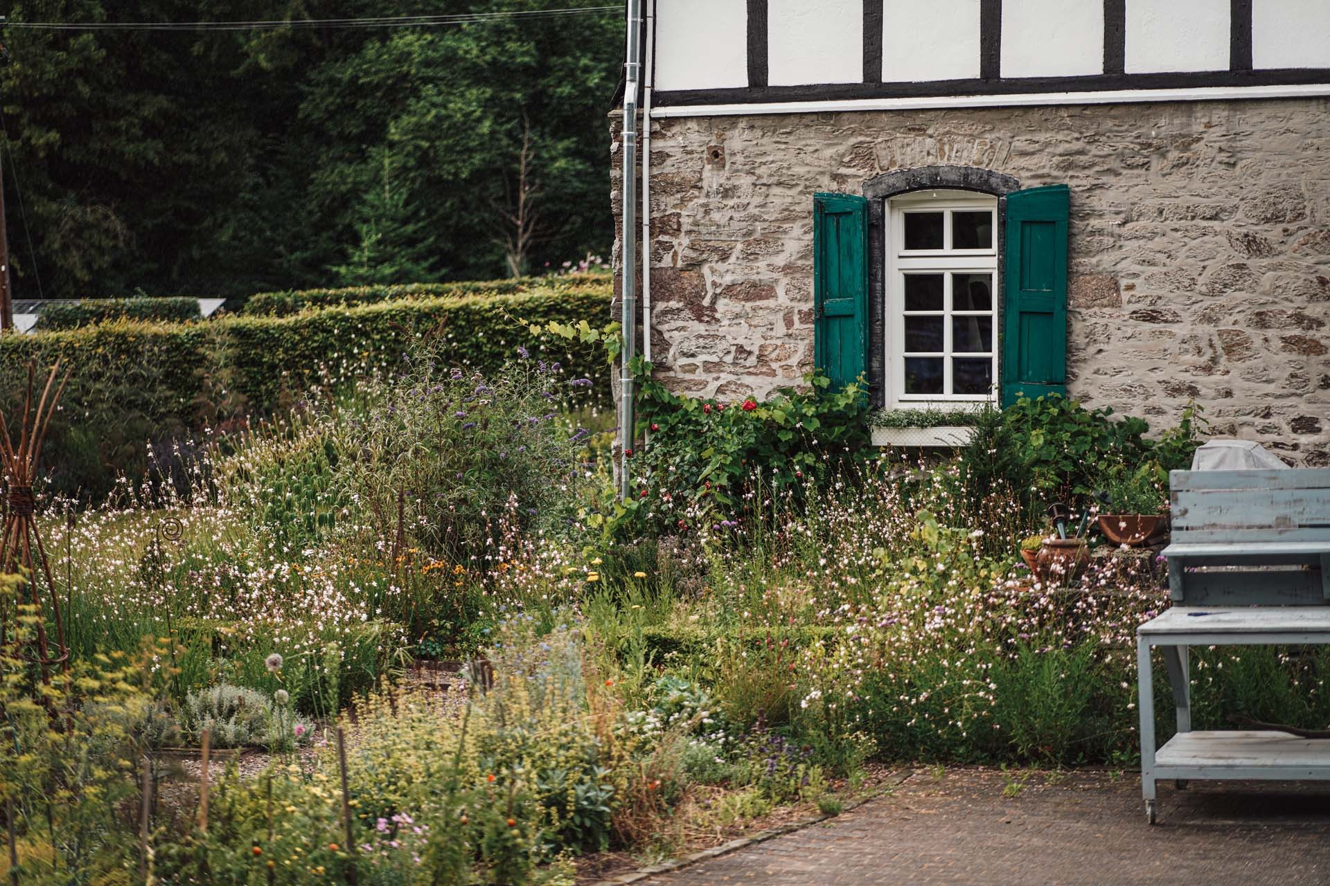 Blühender Garten vor der Mühle mit grünen Fensterläden