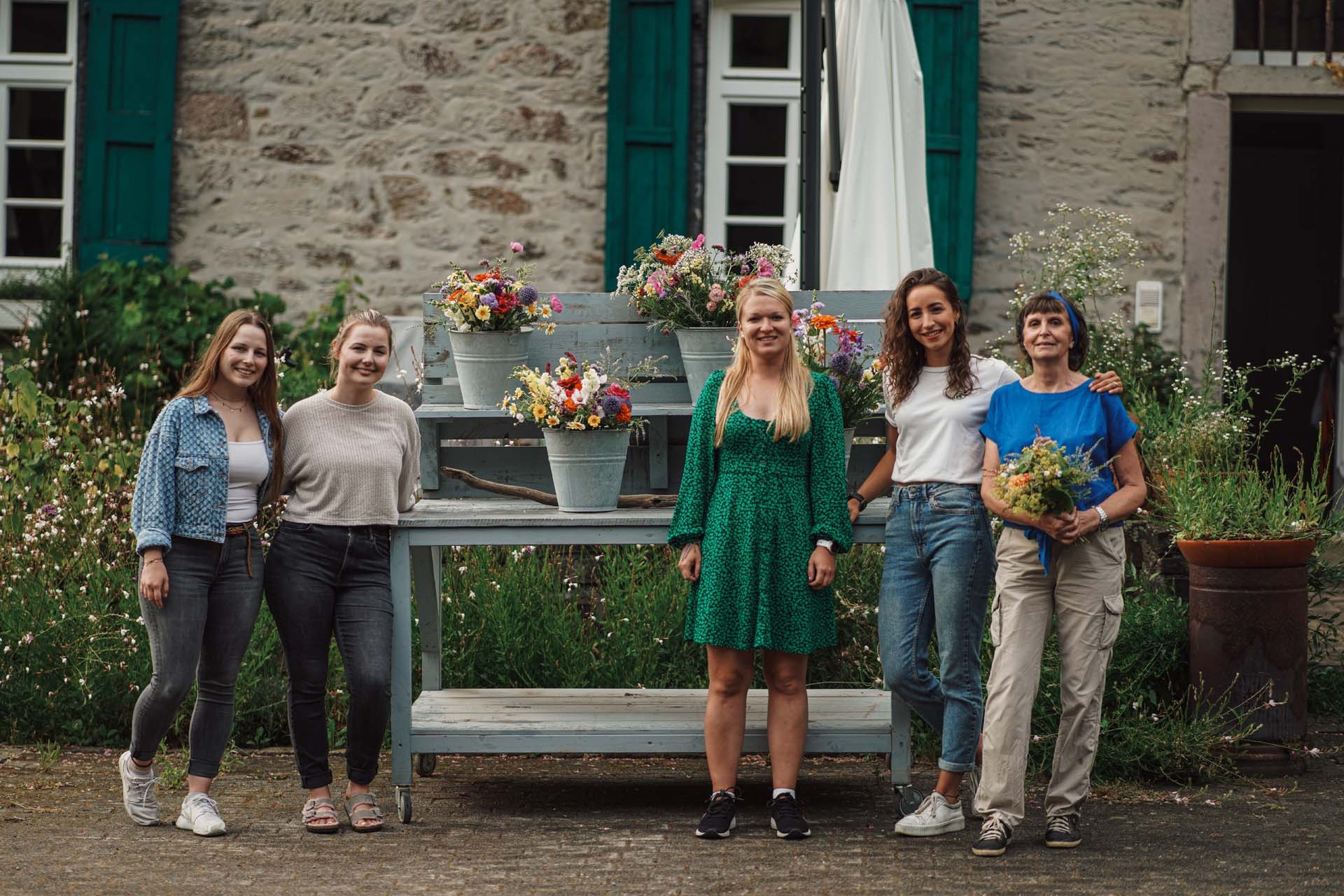 Fünf Frauen neben Blumensträußen im Mühlengarten
