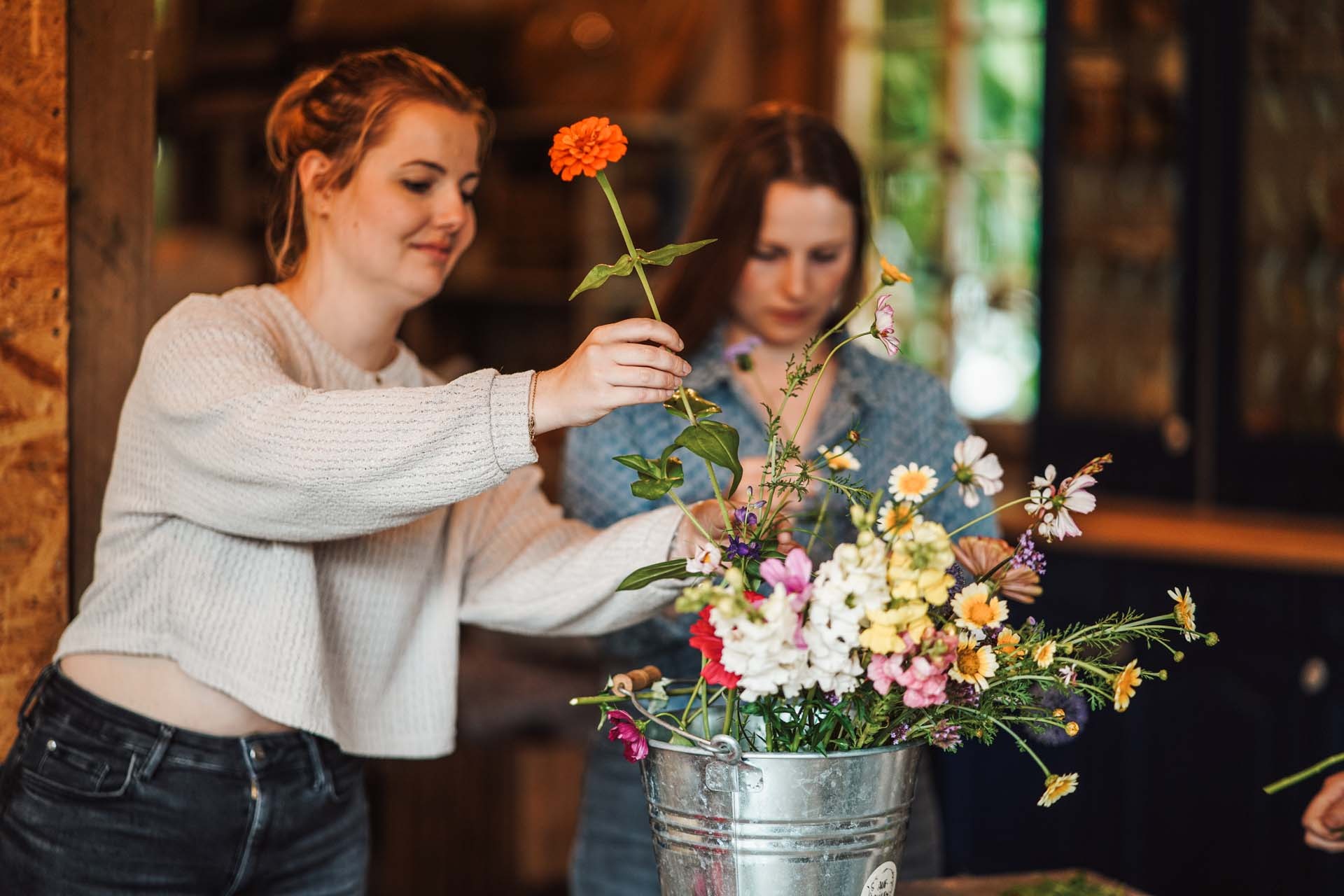 Zwei Teilnehmerinnen gestalten gemeinsam ein Blumenarrangement